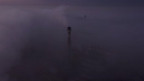 flying around the factory pipe in the morning mist at sunrise. drone view