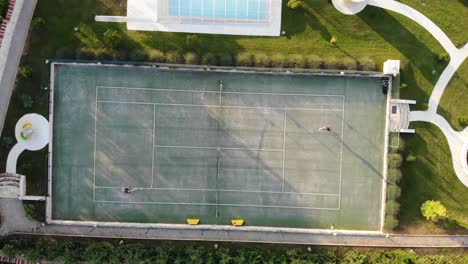 aerial birds eye view of two people playing tennis at golden hour