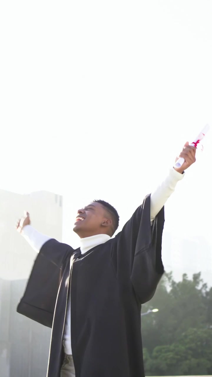 Vertical video: Waving diploma, man in gown fixing cap and tossing it on rooftop, celebrating