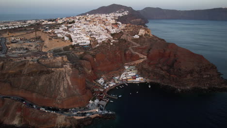 vista aérea de la isla de santorini, grecia, puerto bajo el pueblo de oia y acantilados volcánicos rojos, disparo de drones
