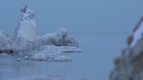 small waves breaking against the ruins of karosta northern forts fortification on the shore of baltic sea on a cloudy winter day, covered with ice, snow and icicles, medium shot