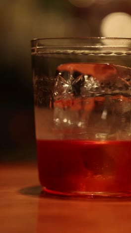 hand stirring a drink with ice at a bar