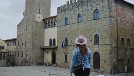 Adult-Woman-On-A-Denim-Jacket-Standing-Nearby-Town-Hall-Of-Arezzo-In-Tuscany,-Italy-On-A-Cloudy-Day