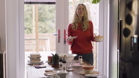 a woman in a kitchen near a dining table and refrigerator