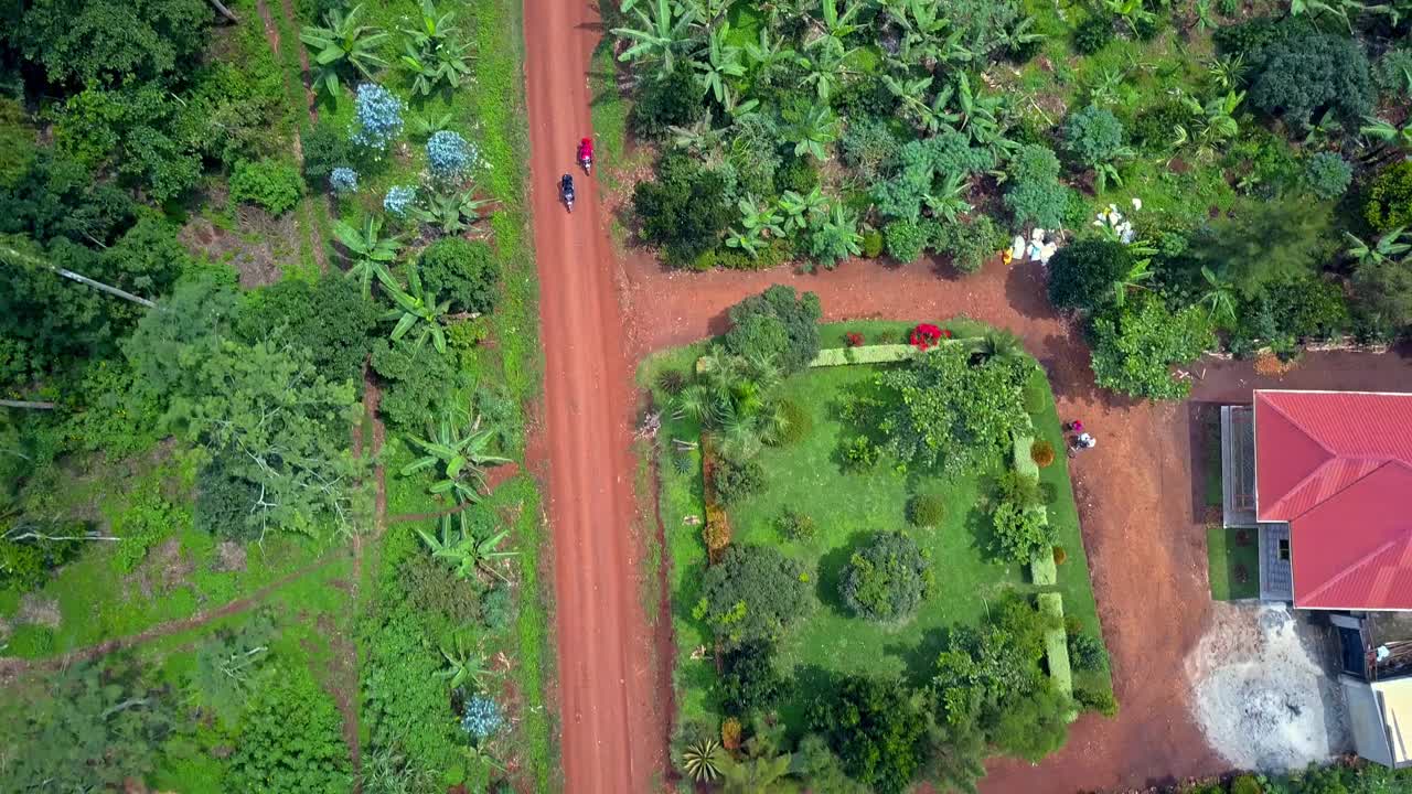Motorcycles Driving On A Dirt Road In Mukono, Uganda - Aerial Top Down