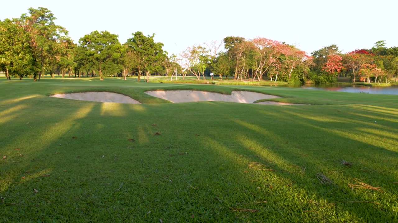 Ampia ripresa dal basso verso l'alto di un lussureggiante fairway verde di campo da golf sotto la brillante luce solare tropicale.