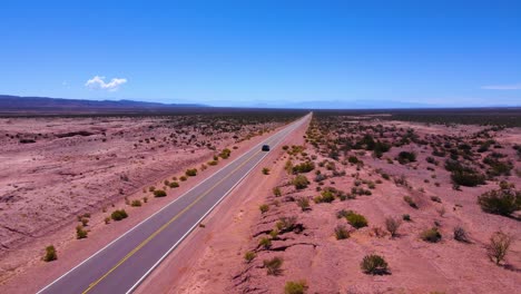 drone shot following a gray car driving through the talampaya national park in la rioja, argentina