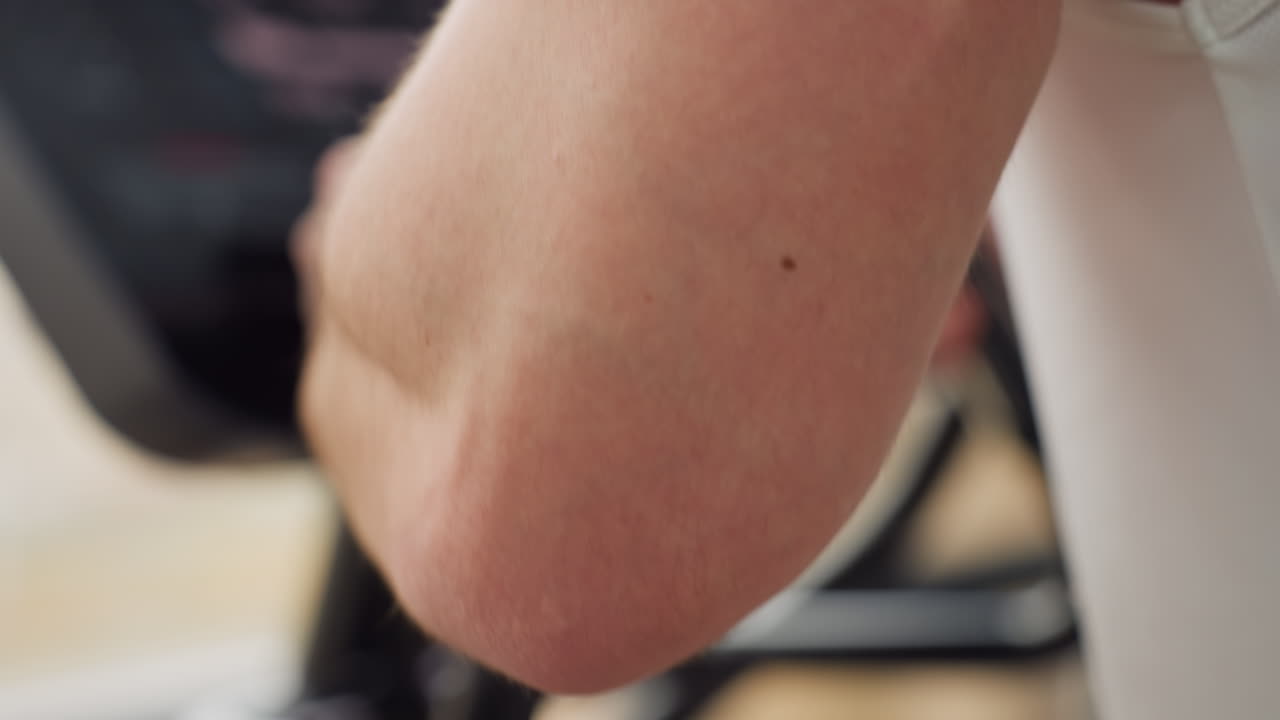 Muscular forearm gripping elliptical trainer handle with firm control while athlete powers through intense cardio session on modern gym machine displaying focus strength and endurance