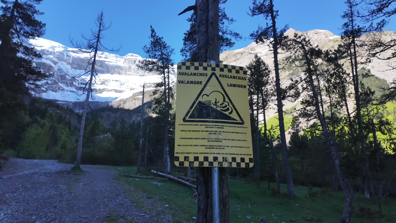 A Yellow sign advising the hikers to stop. Avalanche risk going ahead. Shot in the cirque de gavarnie, a UNESCO site in the French Pyrenees.