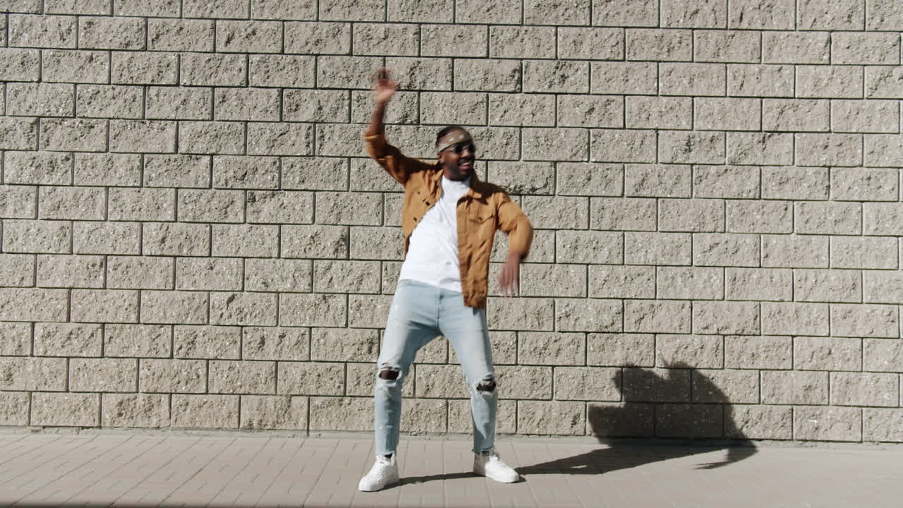 Man Dancing in front of Brick Wall