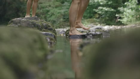 children and adult walking across rocks in a river