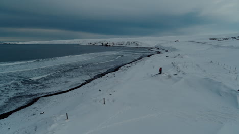 standing a snow covered beach checking the frozen surf in iceland during winter shot with a drone