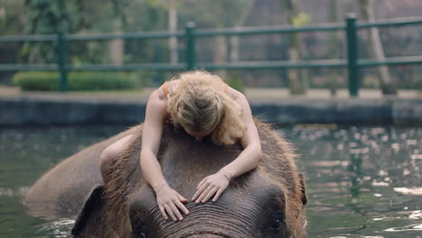 beautiful woman riding elephant in zoo playing in pool splashing water female tourist having fun on exotic vacation in tropical forest sanctuary