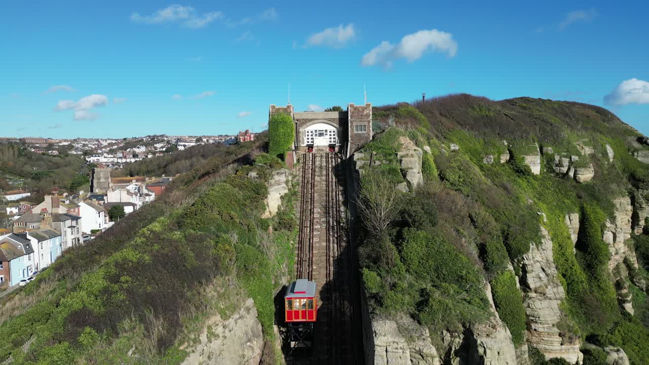 tomada aérea de un dron de hastings, reino unido, cámara volando sobre la playa de stade, barcos de pesca y high street, lejos del ferrocarril de east hill cliff