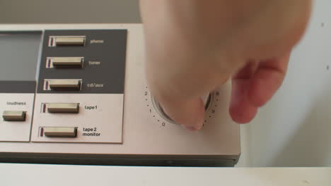 low angle close up shot of adjusting the volume on a silver sound device with the right hand