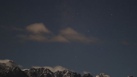 time-lapse of clouds moving over starry sky and mountains in queenstown, new zealand. captures serene nighttime atmosphere