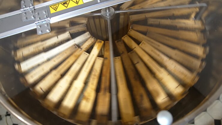 Frames with honeycombs rotating in the centrifuge device for removing honey. Harvest season at bee farm. Close up.