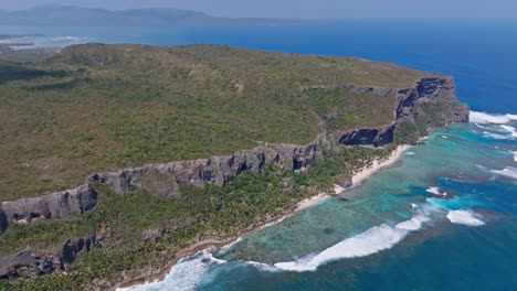 Huge-rock-formation-with-dense-forest-jungle-in-the-ocean,-aerial-view