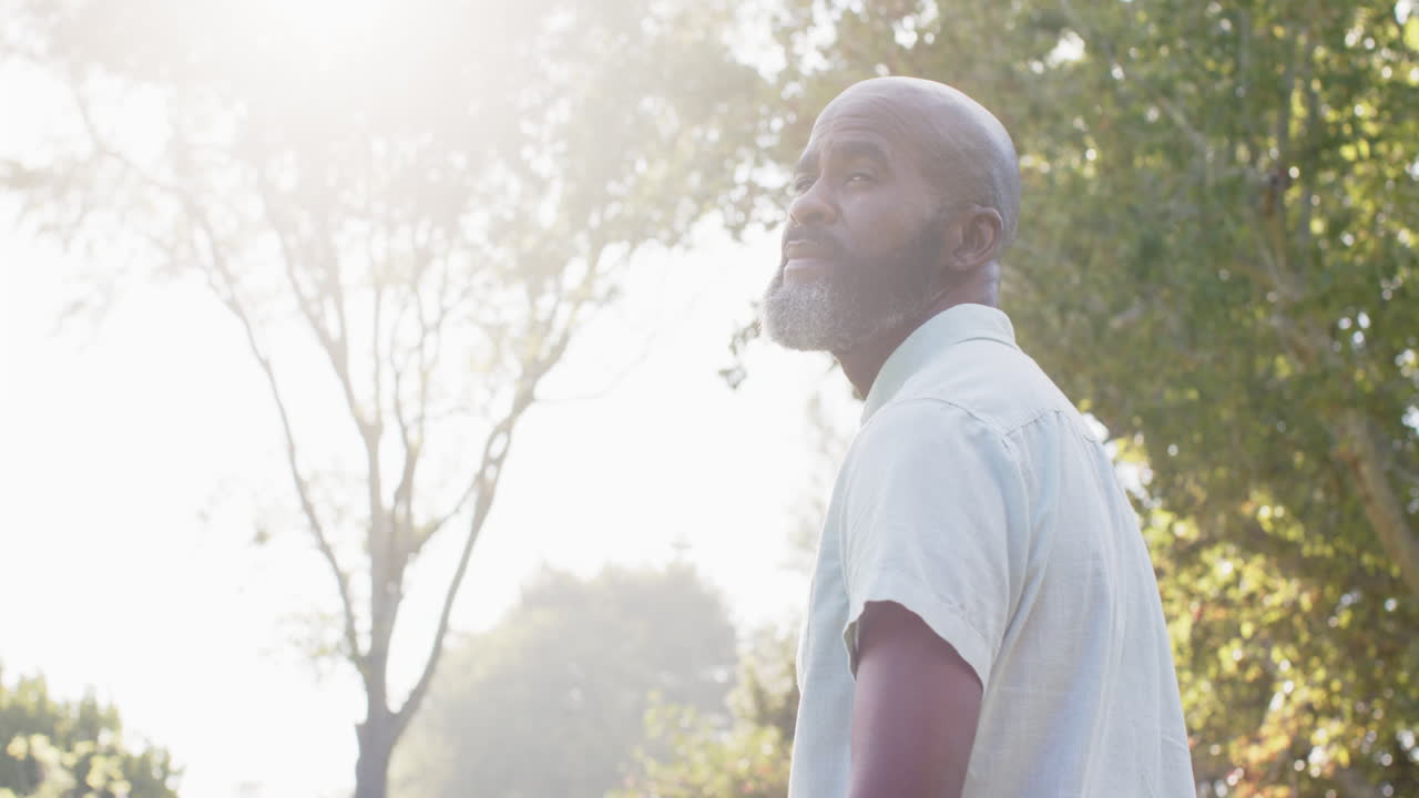 Smiling man enjoying outdoor walk in park with trees and sunlight, copy space