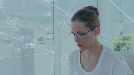 Network-of-connections-against-portrait-of-caucasian-woman-smiling-while-using-computer-at-office