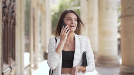 confident young business lady walking and talking on a cell phone