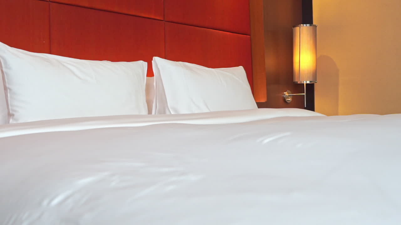 pan a través de una cama de hotel con un cabecero tapizado rojo