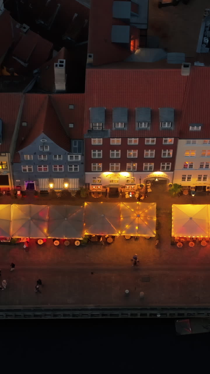 Aerial drone view of the Nyhavn waterfront, canal and entertainment district in Copenhagen, Denmark in the evening. Vertical