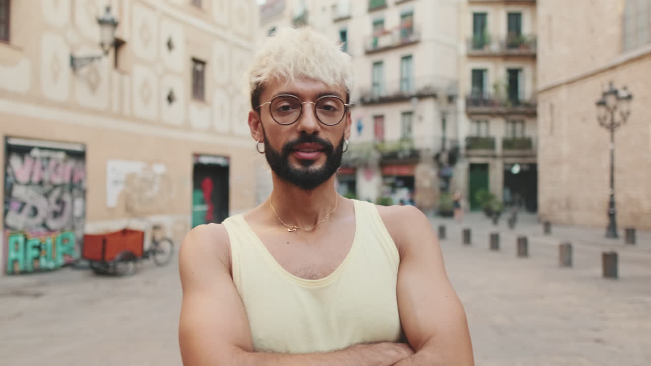 Young Man with Blonde Hair and Beard Standing Confidently in Urban Square