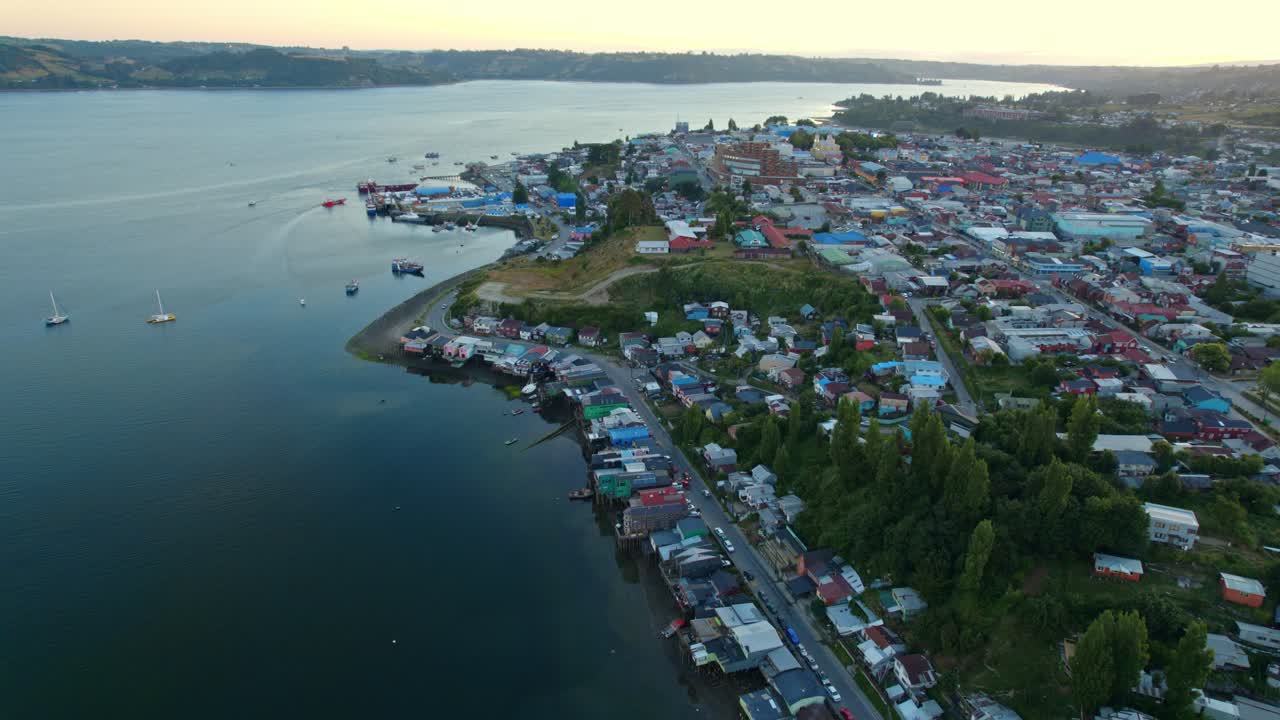 el atardecer panorámico aéreo de drones sobre la bahía de pedro montt palafitos en castro, atardecer, aguas prístinas con la ciudad de la isla patagónica