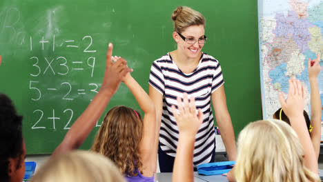 school kids raising hand in classroom