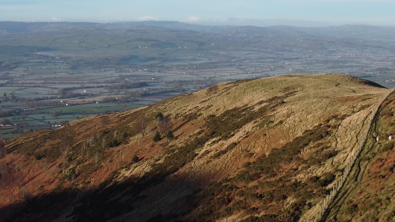 la primera luz del sol en el pico de la montaña de las tierras altas vista aérea a través de la vasta y helada campiña idílica alejarse