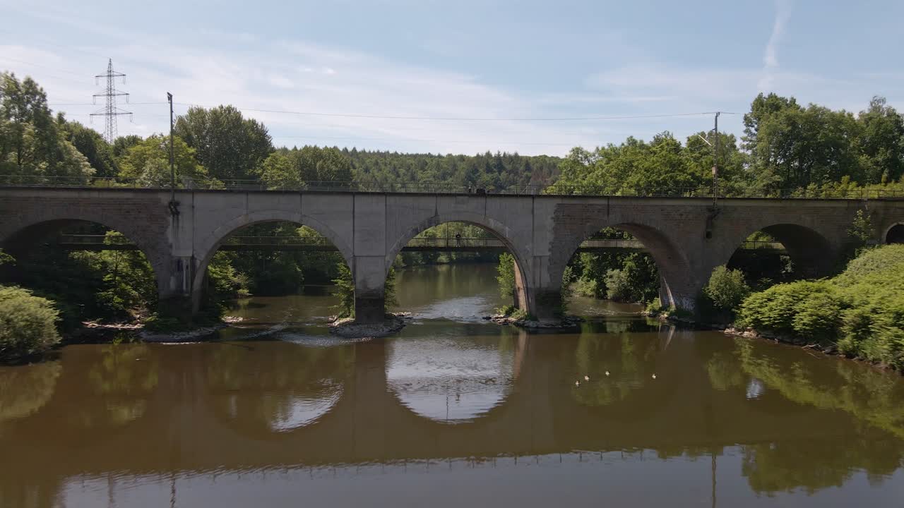 독일 시골의 푸른 강을 가로지르는 기차 가대 발길에 서 있는 사람