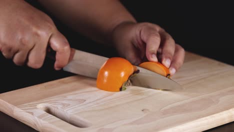 hands skillfully cutting a ripe persimmon