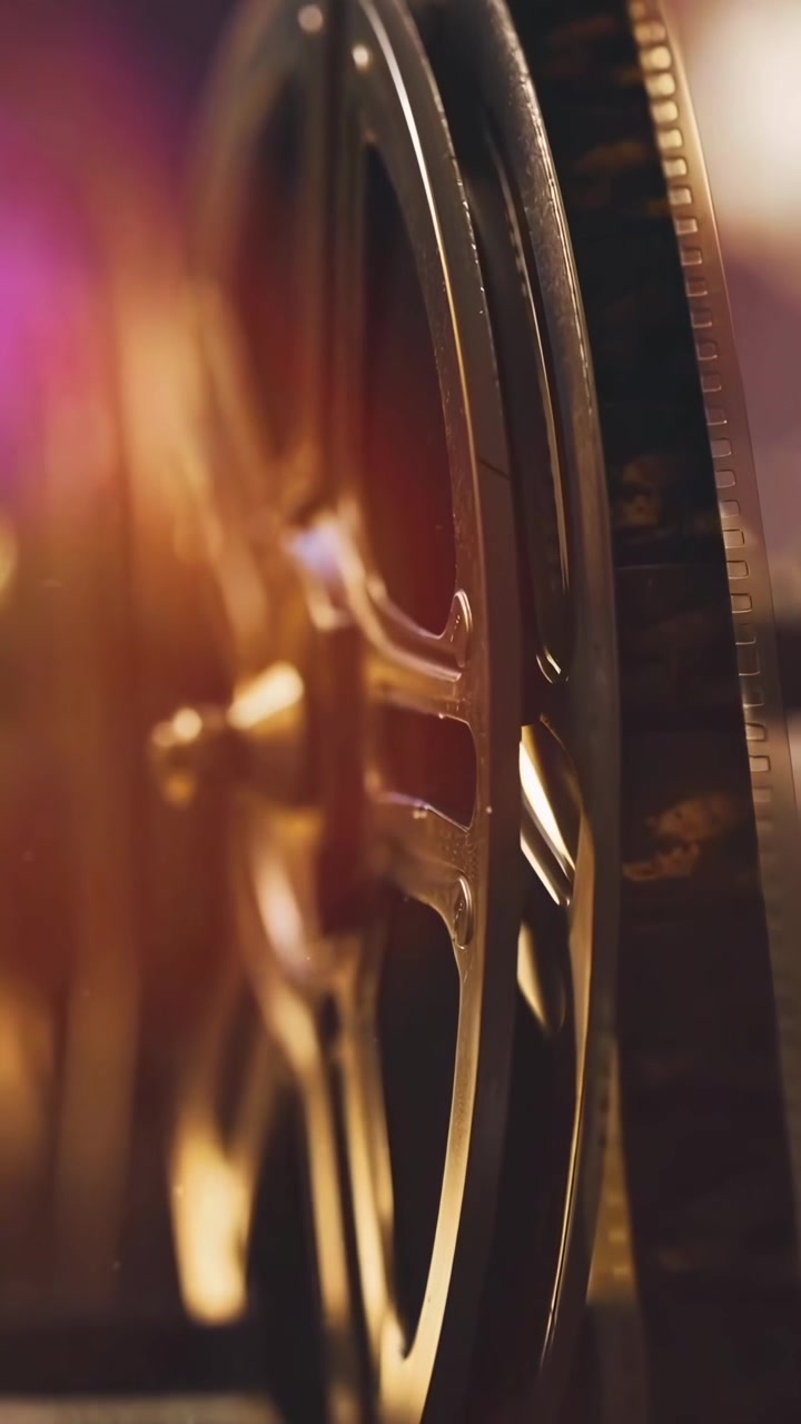 Primo piano cinematografico di una bobina di pellicola che ruota con luce dorata