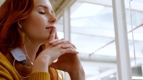 female graphic designer listening music on headphones in office 4k