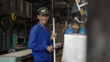 smiling asian worker in blue uniform in a workshop