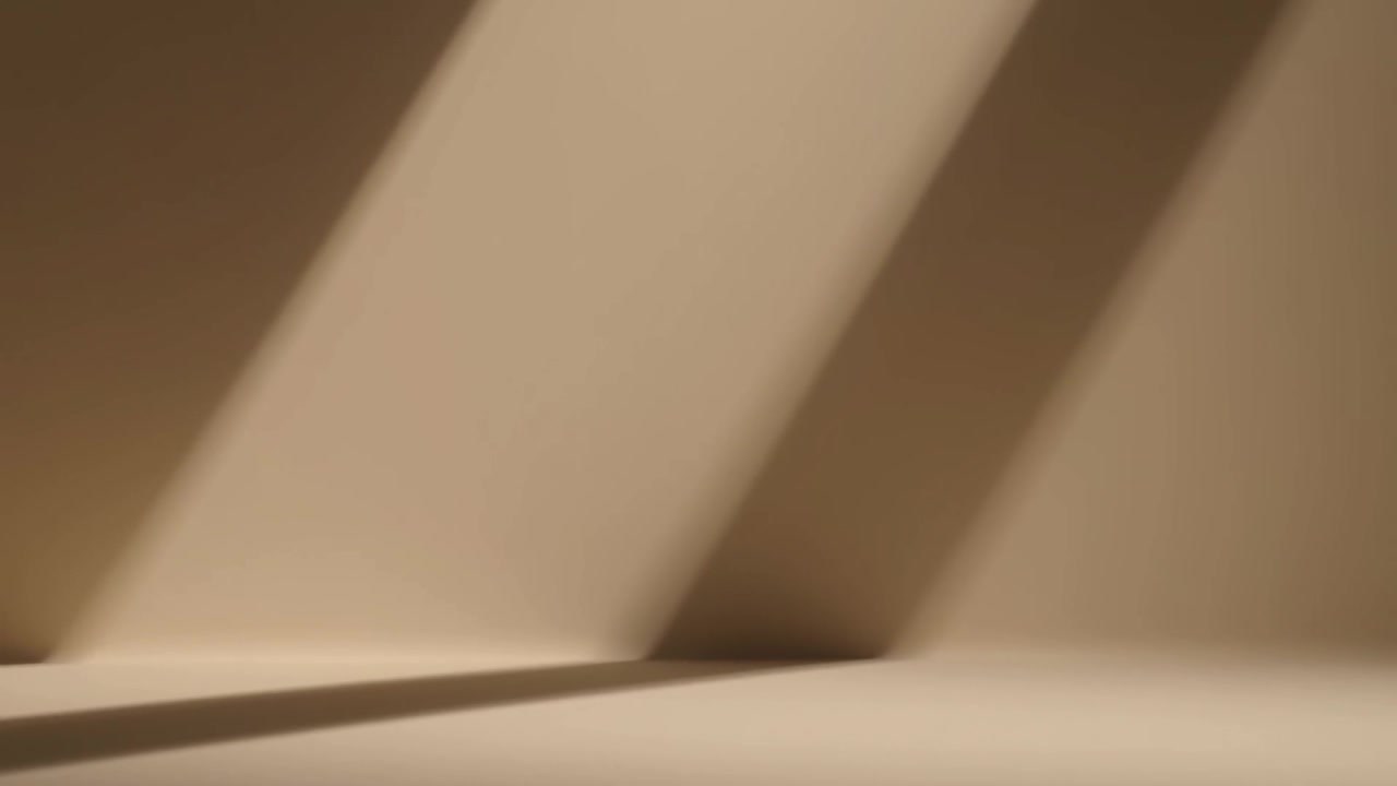 Banda diagonale che si sposta attraverso un angolo beige, mostrando fasce d'ombra mentre la luce entra dal lucernario.