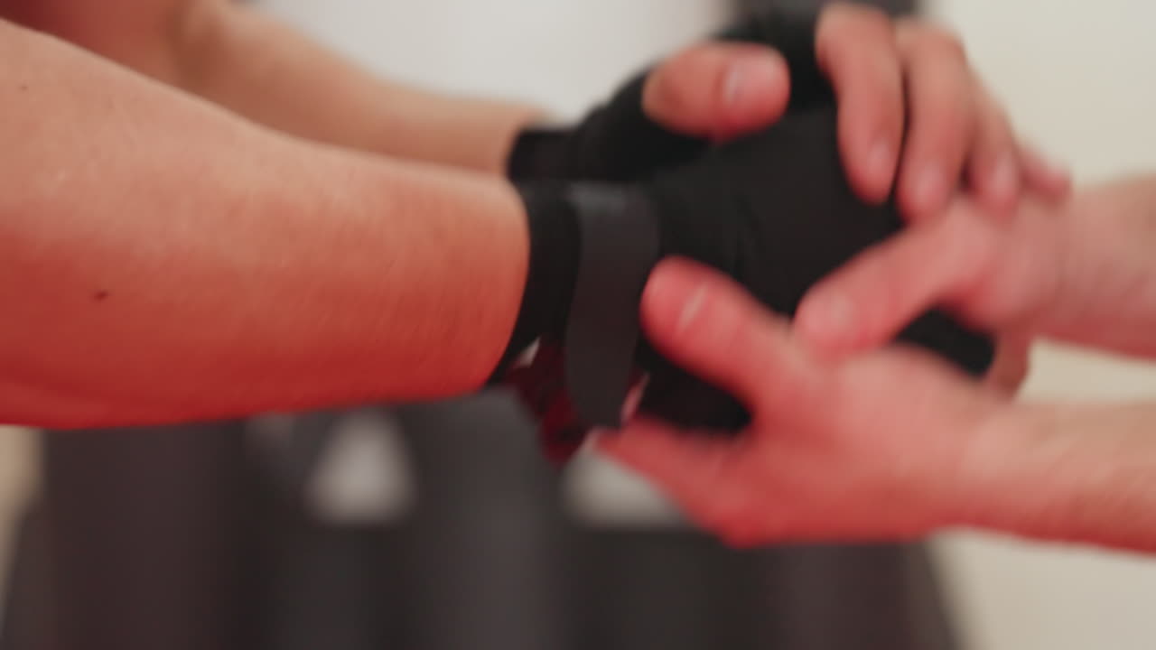 Close up of wrestler hand wrapped in black glove shakes hand with opponent during combat training inside gym, focus on grip strength and readiness for fight, and physical intensity of martial arts practice