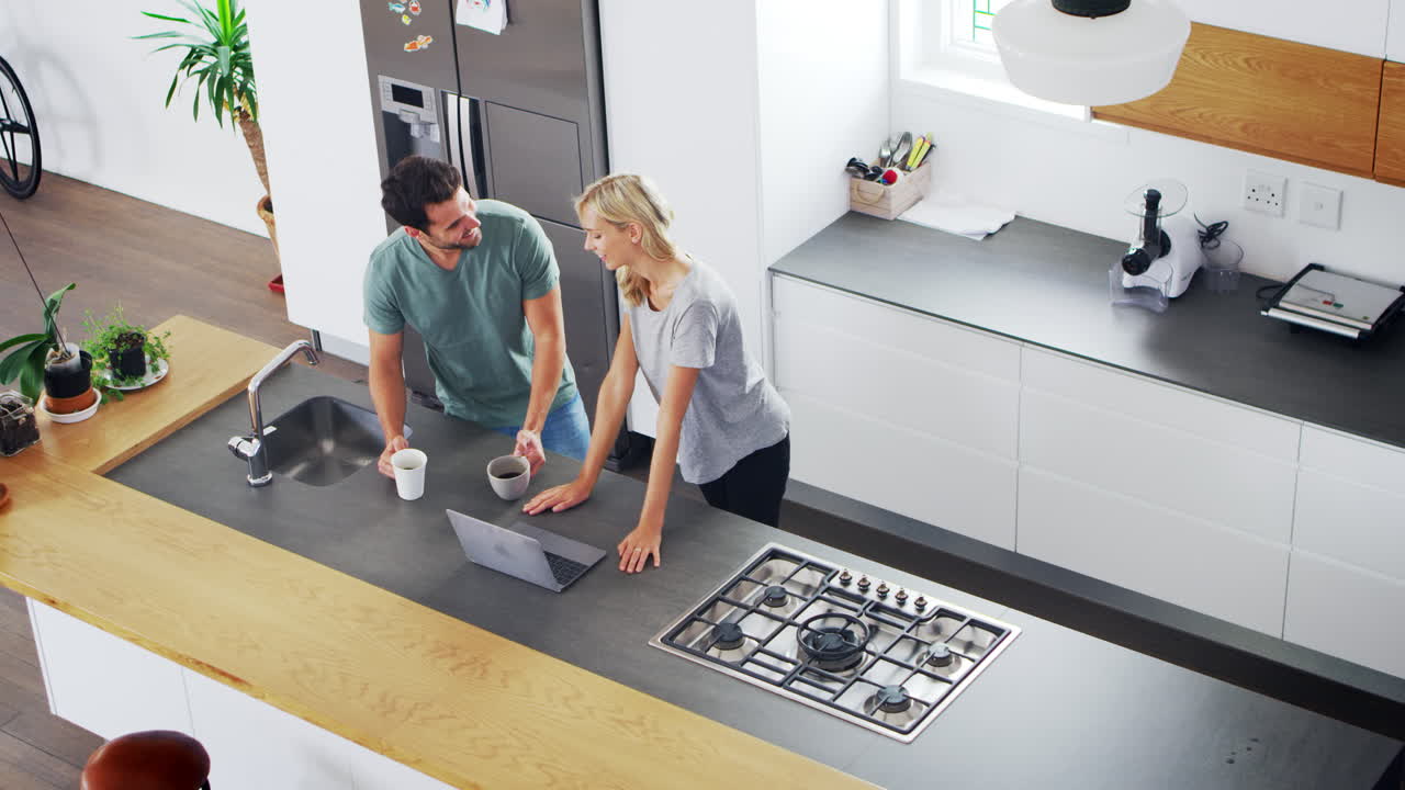 Vista dall'alto di una coppia che guarda il portatile in una cucina moderna