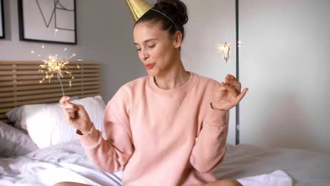 Cheerful woman having fun with sparkler in birthday morning