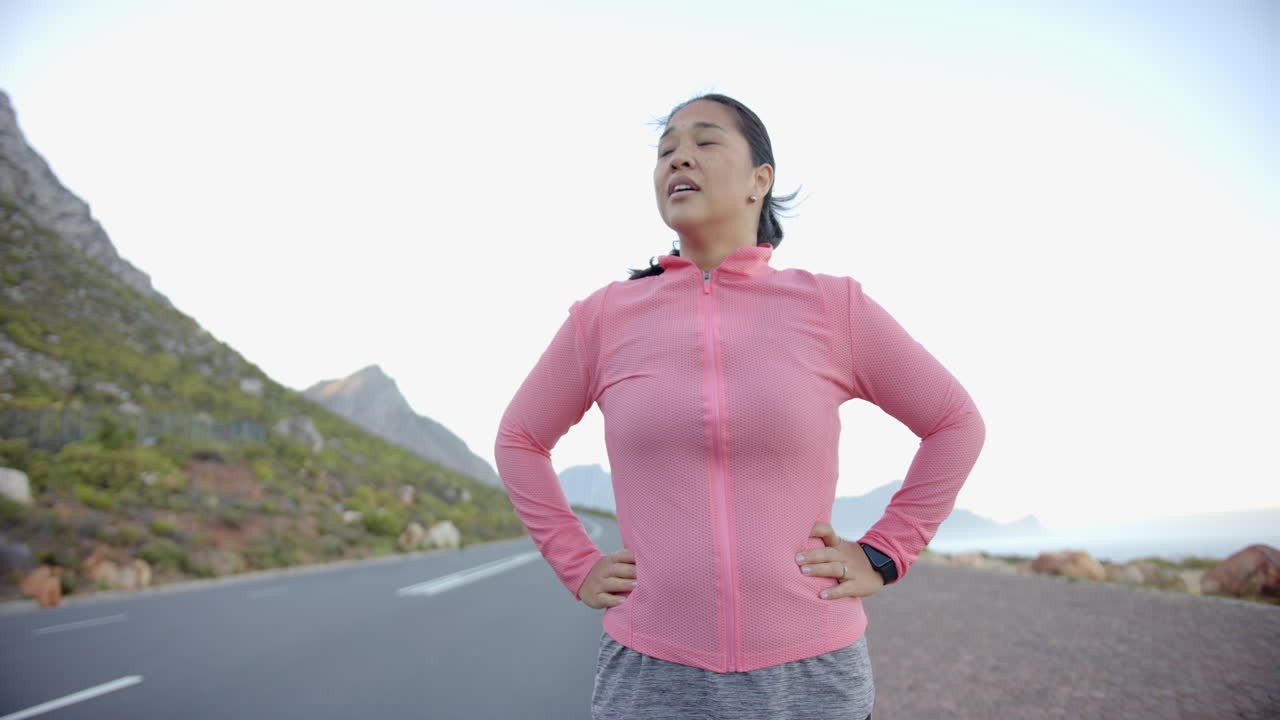 Taking break, woman in sportswear standing on mountain road during hike