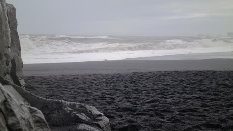 cold rainy day on coast of iceland, black sand beach and rough sea waves