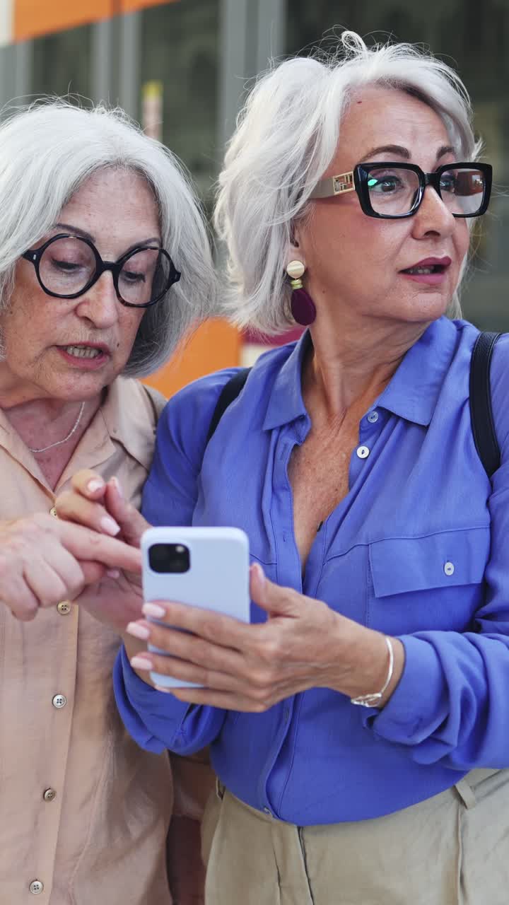 Due donne anziane che discutono e indicano lo schermo di uno smartphone