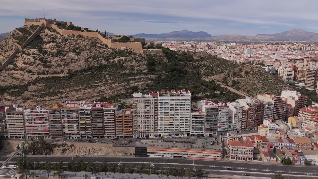 Droneoptagelse af Santa Bárbara Slot på bjerget Benacantil med udsigt over Alicantes tætte bybillede. Middelhavs kystby på Costa Blanca i Spanien med bjerge i baggrunden.