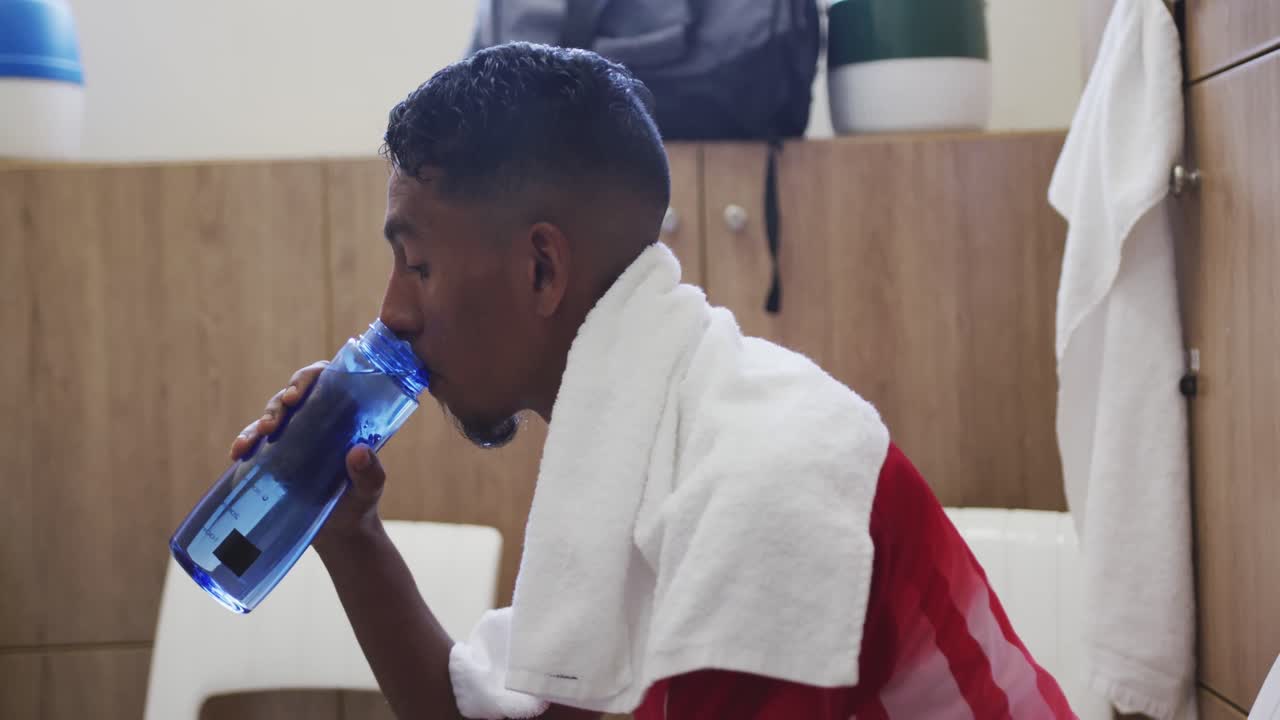 jugador de fútbol bebiendo agua en el vestuario