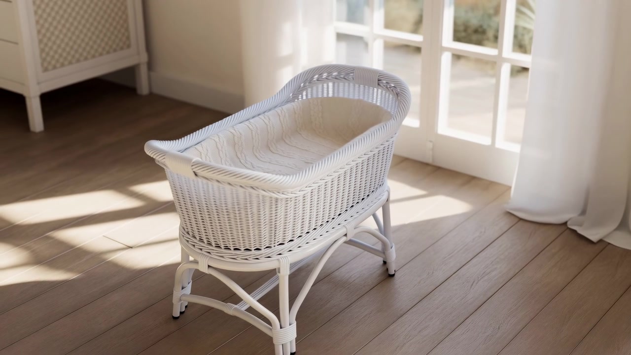 Empty white wicker bassinet rests on curved stand inside bright nursery beside glass paneled door and sheer curtain, showing knitted padding, woven rattan detail, soft cream tones, gentle daylight