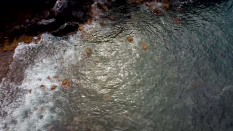 vista aérea de las olas rompiendo en las rocas en el mar azul de la isla de madeira