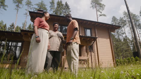 View-From-Below-Of-A-Middle-Aged-Woman-Standing-Outside-Her-Home-And-Saying-Goodbye-To-Her-Relatives