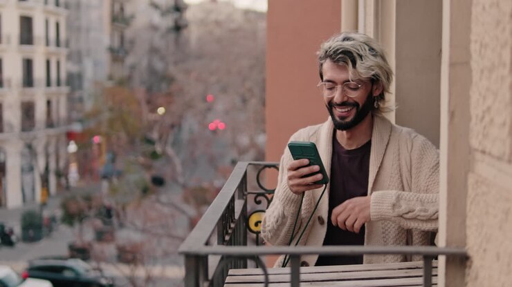 Gay Couple at Home on Balcony With Smartphone