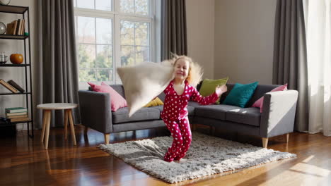 playful child jumping with a pillow in a sunny living room